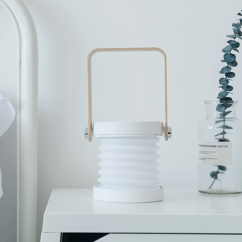 Lykt Lanta LED lantern in Arctic White with a collapsible white shade, durable grey base, and a smooth wooden handle, offering elegant and versatile lighting